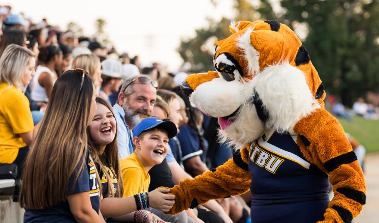 Family Weekend 2023 Tiger mascot giving a girl a high five in the stands at a football game