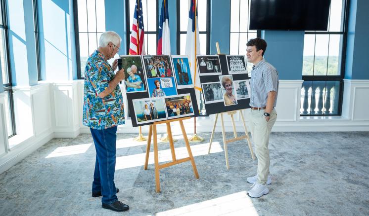 Two males inside standing in front of posters on easles