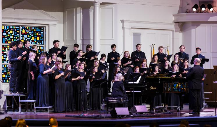 Men and women in choir singing on stage in a chapel