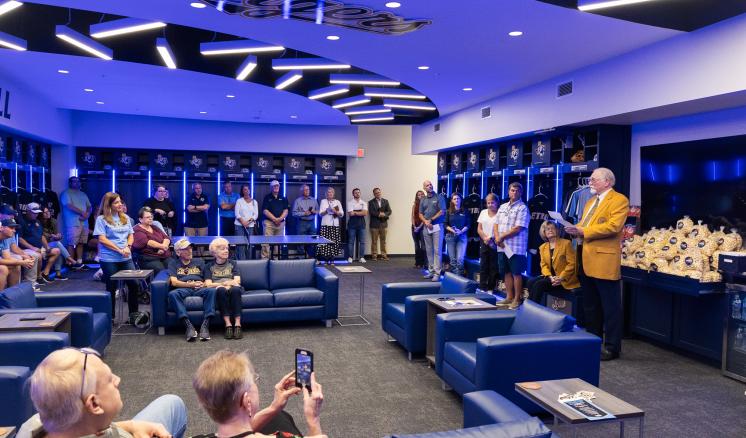 A group of men and women in a blue lit locker room 