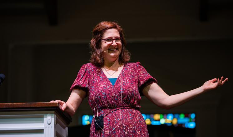 Woman speaking on a stage behind a podium