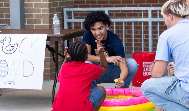 MISD Fall Festivals 2023 Three people interact around a colorful inflatable pool; a child in red, and two adults, one with dark hair and one blonde.