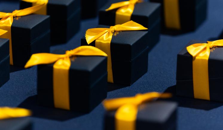 Close up image of navy blue ring boxes with yellow tied ribbon 