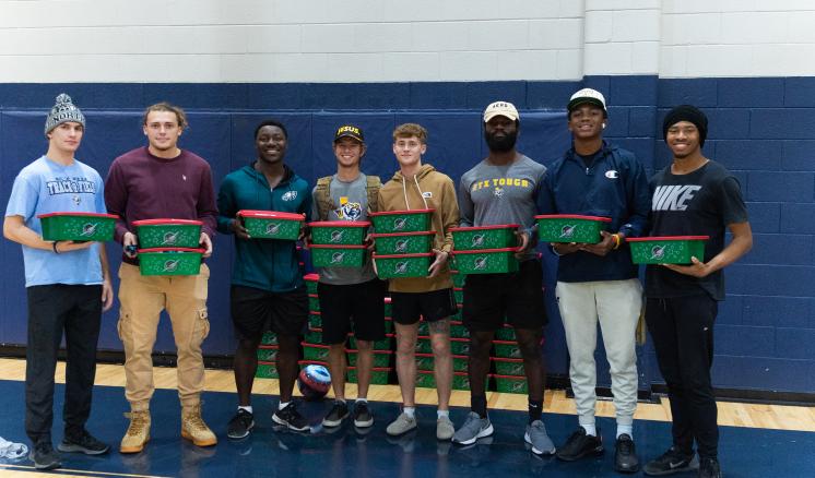 Group of male students smiling at the camera holding Operation Christmas Child boxes 