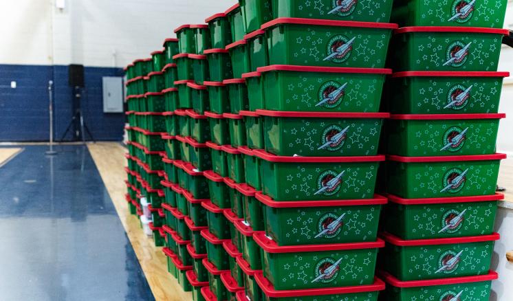 Green and red Operation Christmas Child boxes stacked on top of each other in gymnasium