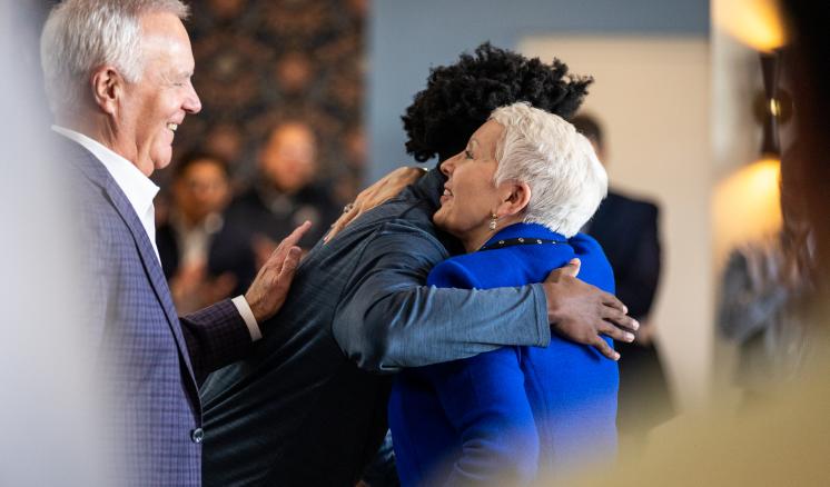 Student hugging older woman in residential hall lobby 