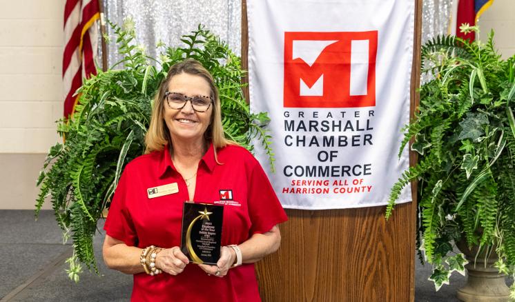 Woman posing with employee of the year award smiling at the camera 