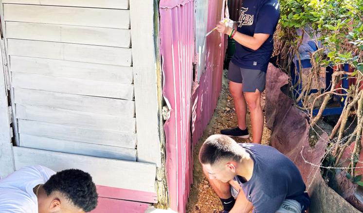 Three men painting the outside of a building white 