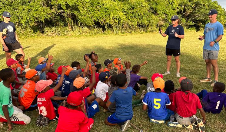 Two men talking to a group of young baseball players 