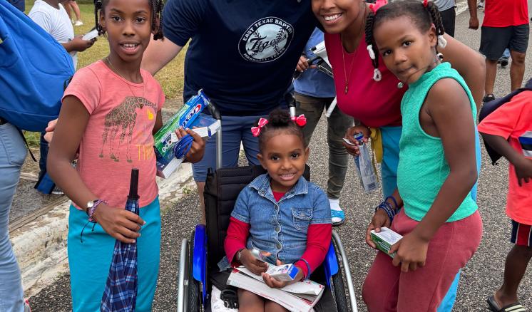 Man smiling with his arms around a group of young girls 