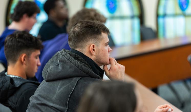 Male student listening to a speaker in a classroom 