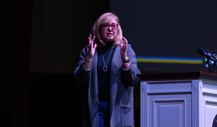 Woman speaking on a stage behind podium