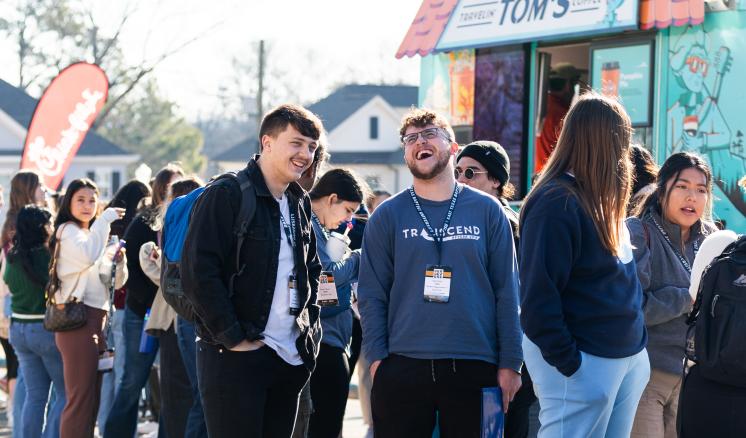 Students laughing with each other in a line for a food truck 