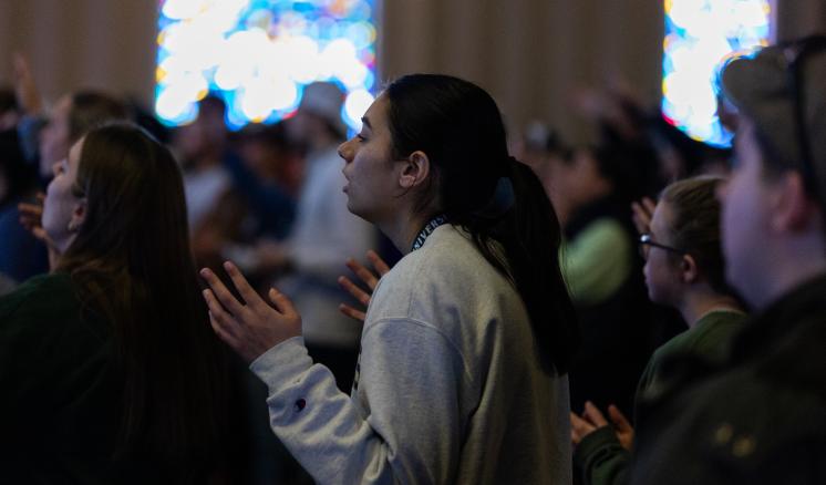 2024_casl_friday_0199 Female student worshiping with her eyes closed in a chapel