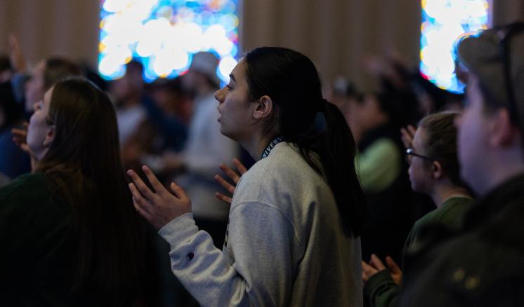 Female student worshiping with her eyes closed in a chapel