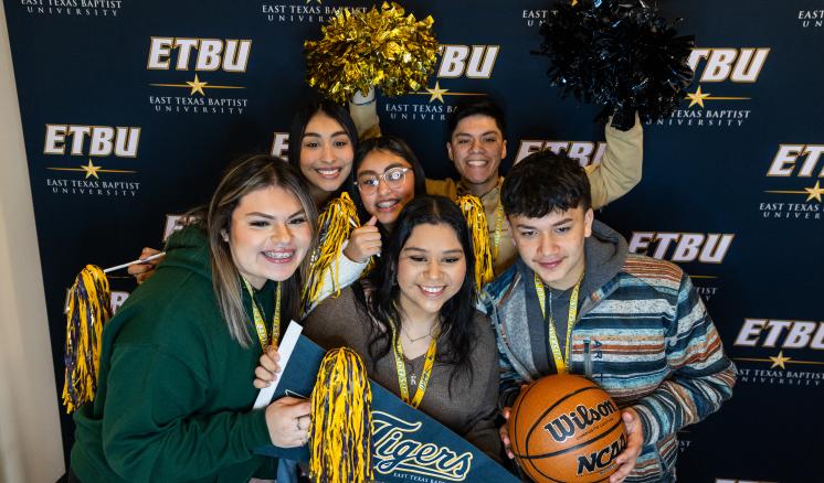 A group of students smiling at the camera with pom poms 