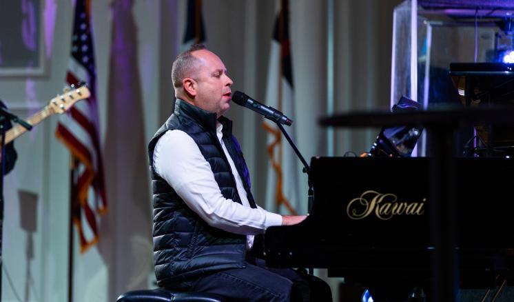 2024_spiritual_renewal_monday_chapel_0043 Man sitting at piano singing into microphone