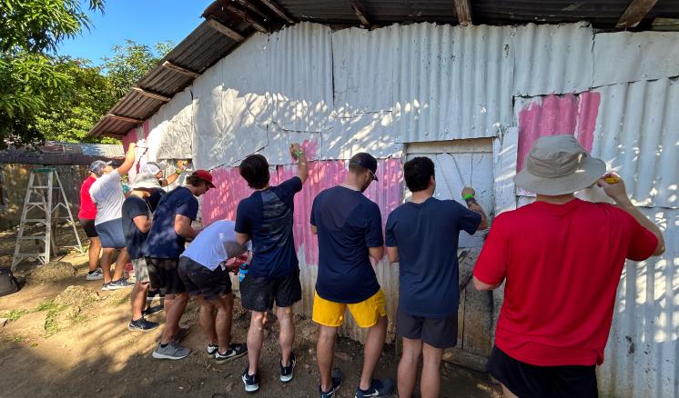 Group of men painting the side of a building 