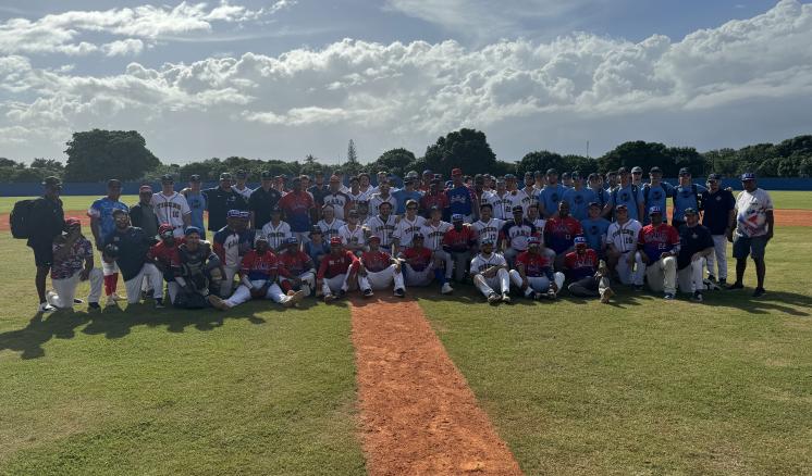 Two baseball teams smiling outside on a baseball field 