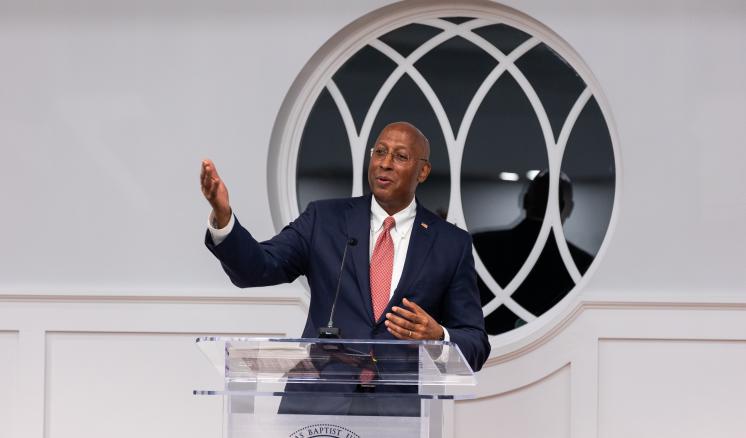 r63_0950 Man speaking behind podium with arm extended