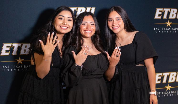 Three senior students show off their rings at ETBU's ring blessing ceremony