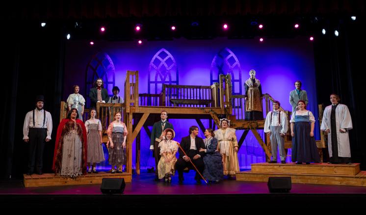 The cast of the Spring 2024 production of Jane Eyre the musical pose for a photo on stage at Memorial City Hall in downtown Marshall, Texas