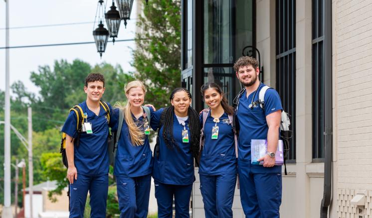 ETBU’s Teague School of Nursing Awarded Over $333,000 to Address Nursing Shortage and Enhance Training Five students stand side by side outside of building in nursing school scrubs, some holding textbooks and carrying backpacks