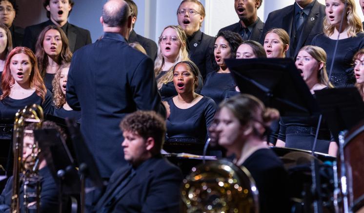 A group of people singing together in a concert choir on a stage