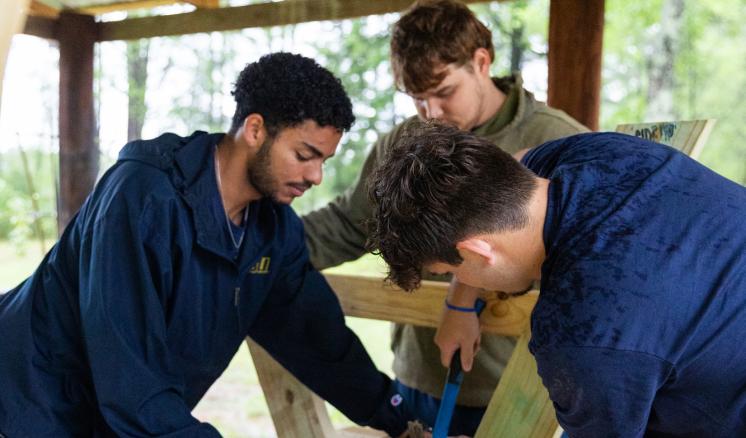A group of people woodworking together building a picnic table