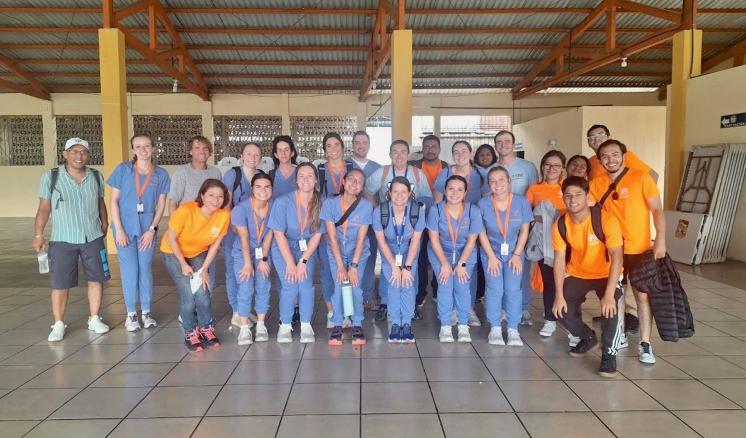 A group of students in nusing scrubs standing together on a tile floor inside