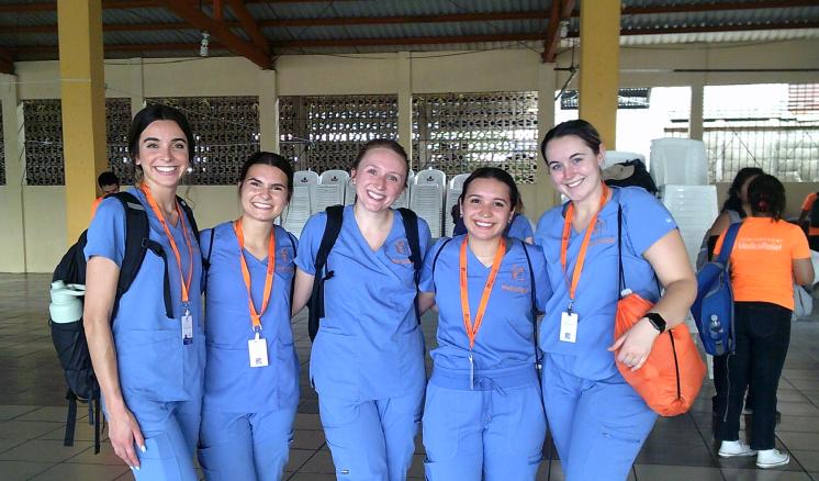 A group of people stood in nursing scrubs on a tile floor inside