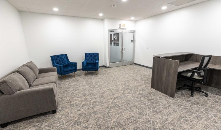 Inside of a building with carpeted flooring, couches, and comfy chairs