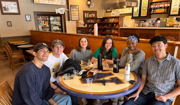 A group of people seated at a table smiling with beverages upon it