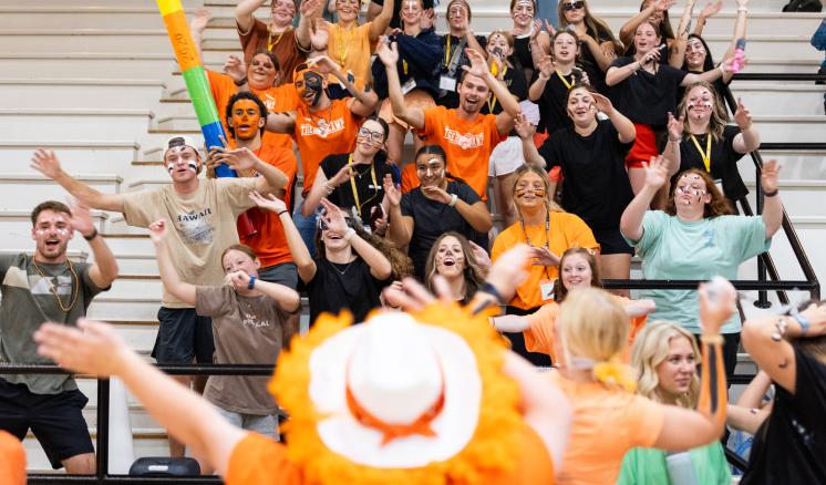 A group of students with their arms up in happiness in a large gym