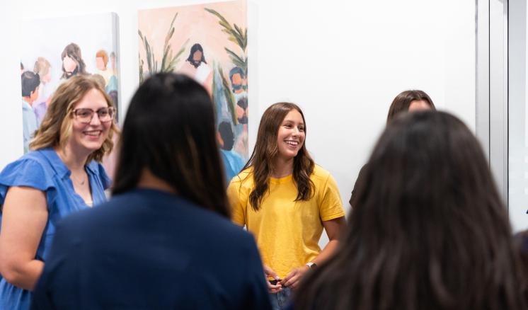 Several people stood together in a circle smiling and talking