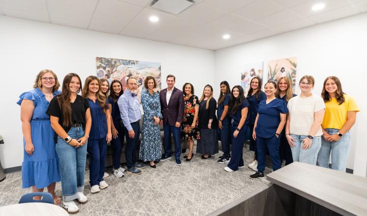 A group of people stood together in a brightly lit room in various clothing types smiling