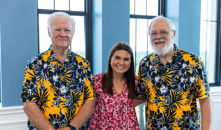 2 men and 1 woman stood smiling together in a group in floral clothing