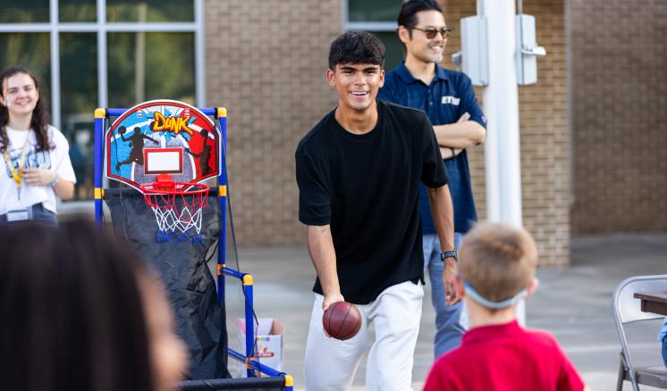 A man throwing a basketball to a small child at a fall festival
