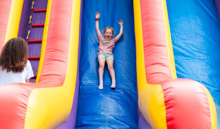 a child sliding down a colorful inflatable slide