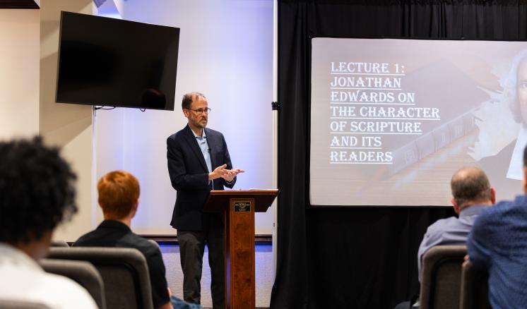 A man standing behind a podium speaking to a crowd inside