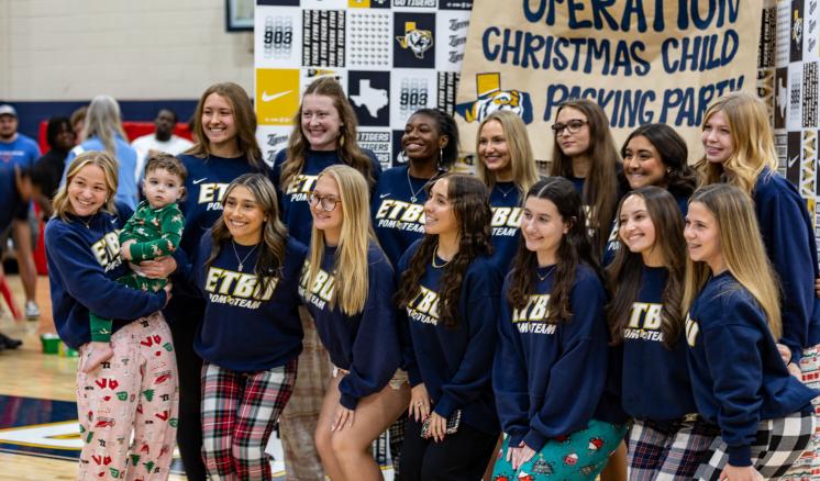 A group of women standing together for a photo in front of a backdrop