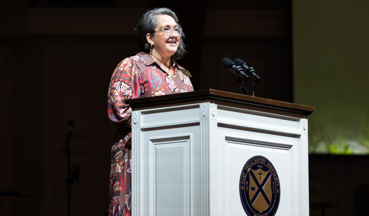 A woman in formal attire stood behind a podium addressing an audience