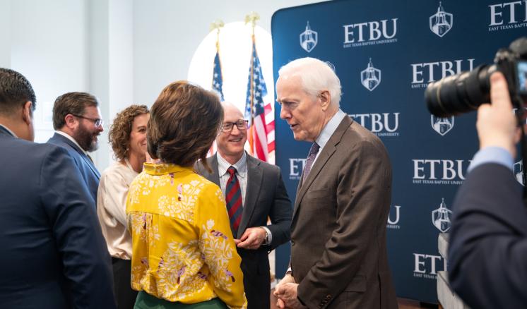 A man and a woman talking together in a large crowded room