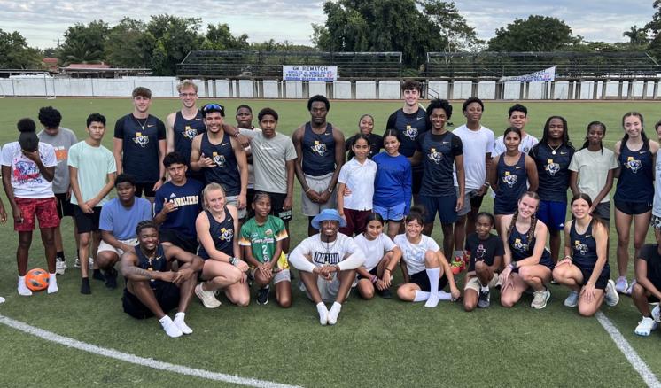 A large group of people outside on a sports field posing for a group photo