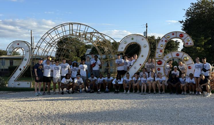 a large group of people standing in front of a sign that reads 2026