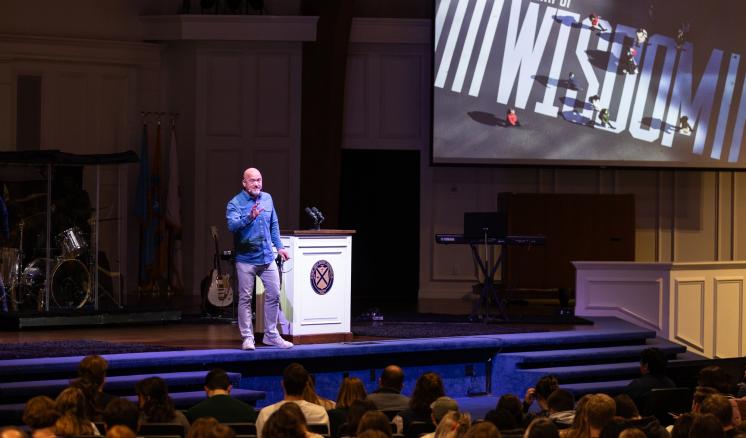 A man on stage behind a podium addressing an audience