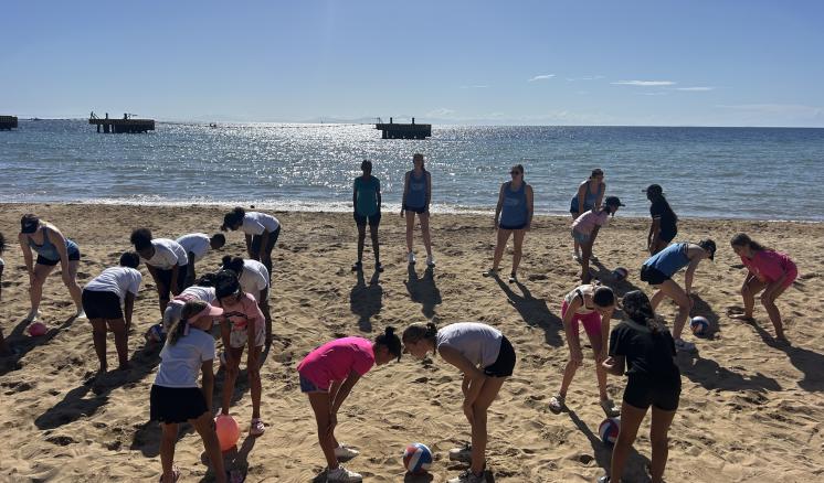a group of people standing together on the beach with volleyballs