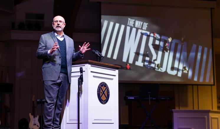 A man on stage behind a podium addressing an audience