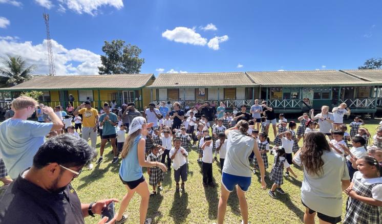 College students laughing and dancing with children outside