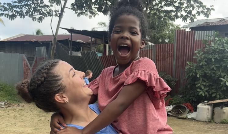 A woman holding up a small child both laughing and smiling